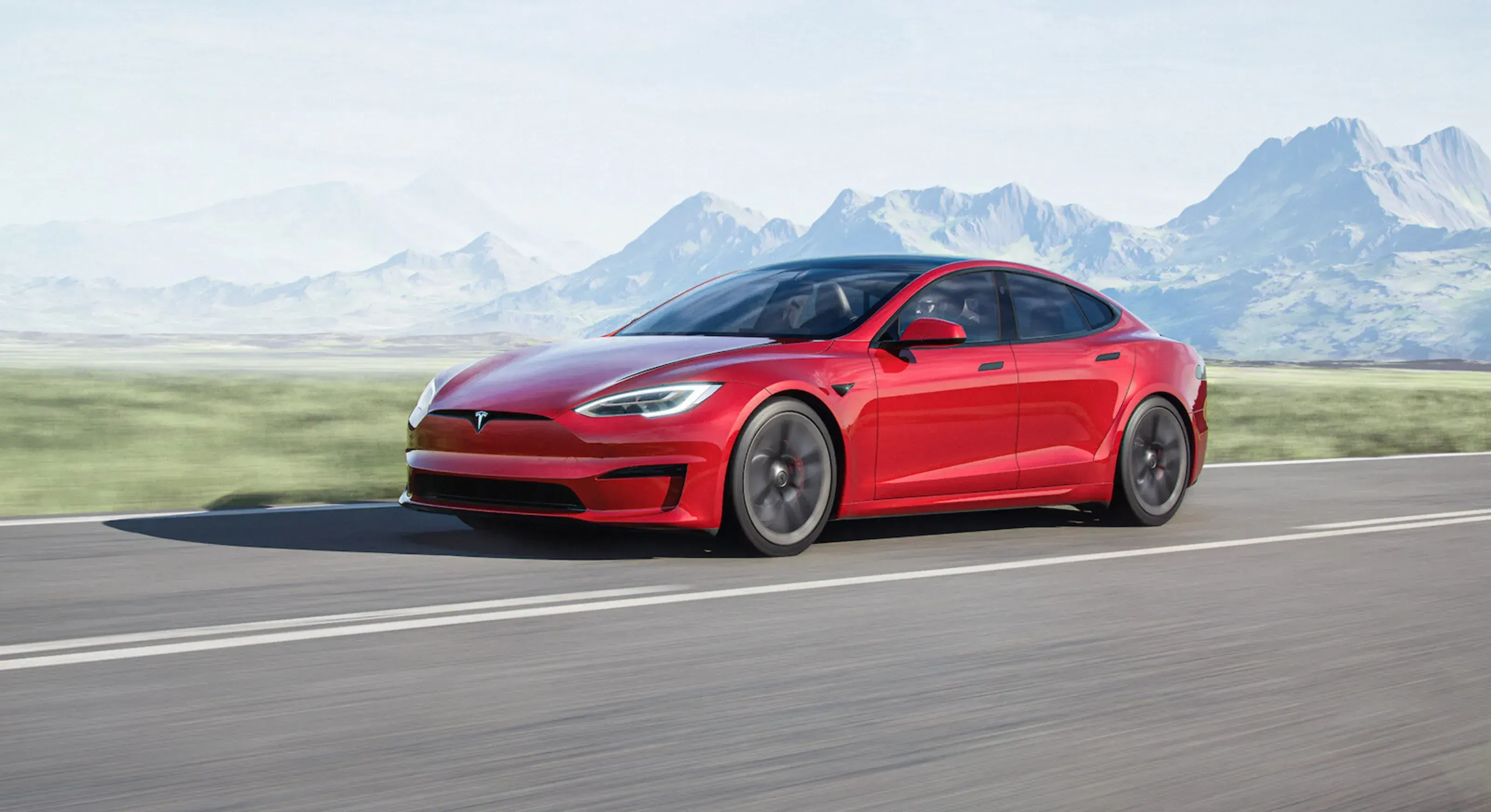 Tesla Model S berkendara cepat dengan pegunungan di latar belakang